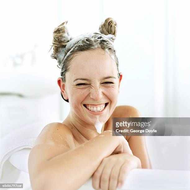 portrait of a comical young woman in a bathtub - se laver les cheveux photos et images de collection
