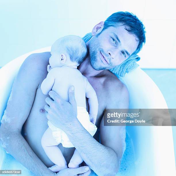elevated view of a man holding a baby girl (6-12 months) in a bathtub - genderblend stock-fotos und bilder