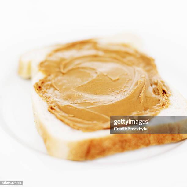 close-up of peanut butter spread on a slice of white bread - slice stock pictures, royalty-free photos & images