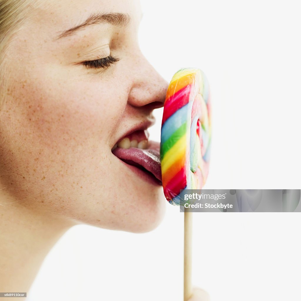 Side profile of a teenage girl licking a lollipop