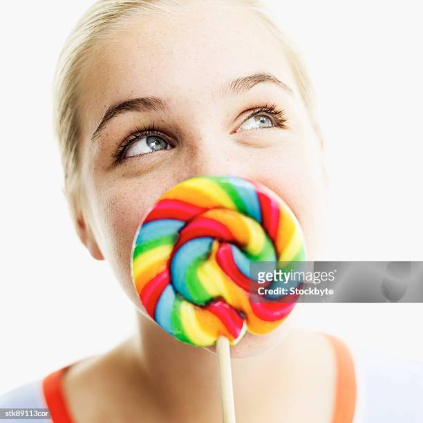 close-up of a teenage girl holding a lollipop in front of her face - her fotografías e imágenes de stock