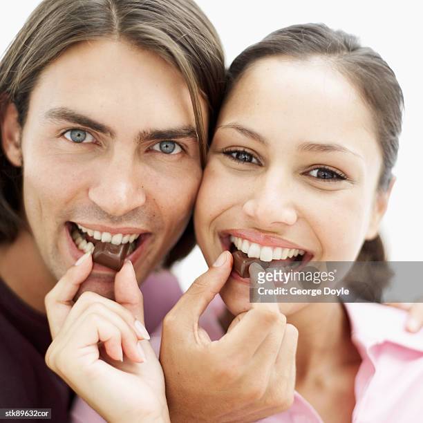 close-up of a couple feeding each other chocolate and smiling - other stock-fotos und bilder
