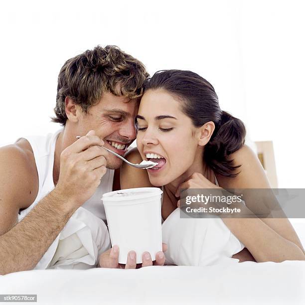portrait of a young couple eating ice-cream from the ice-cream tub - gefrorene süßspeise stock-fotos und bilder