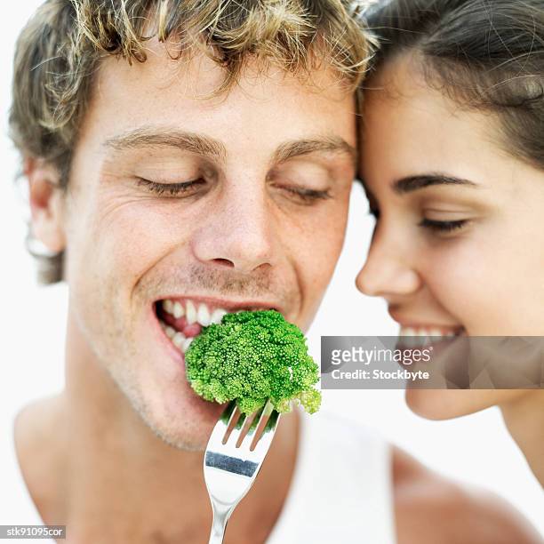 close-up of a woman feeding a man broccoli on a fork - crucifers stock pictures, royalty-free photos & images