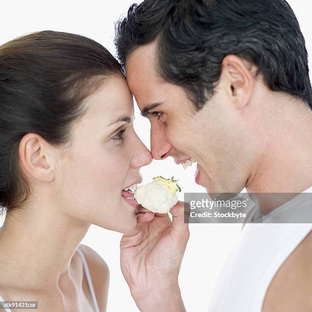 couple sharing a piece of cauliflower - kreuzblütengewächse stock-fotos und bilder