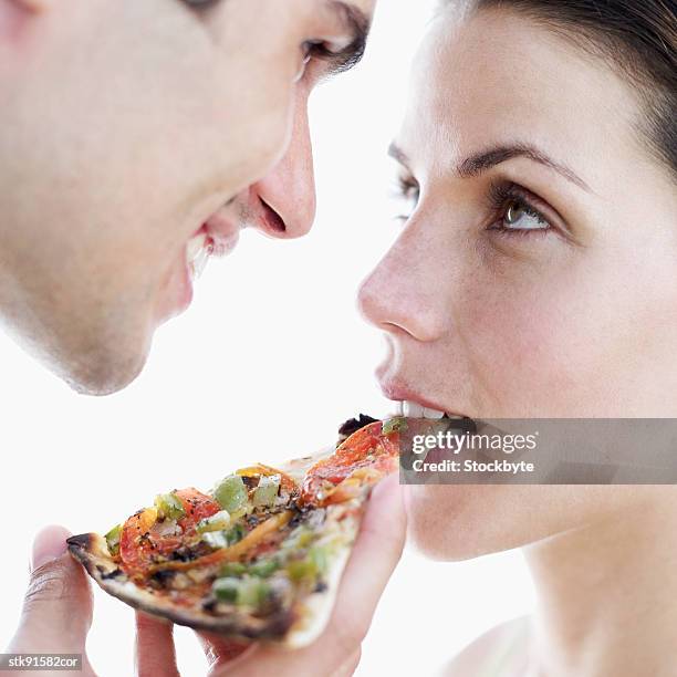 close-up of a man feeding a woman a slice of pizza - slice stock pictures, royalty-free photos & images