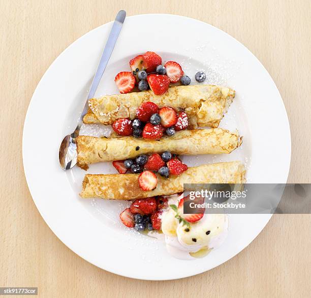 elevated view of a plate of crepes served with berries and ice cream - gefrorene süßspeise stock-fotos und bilder