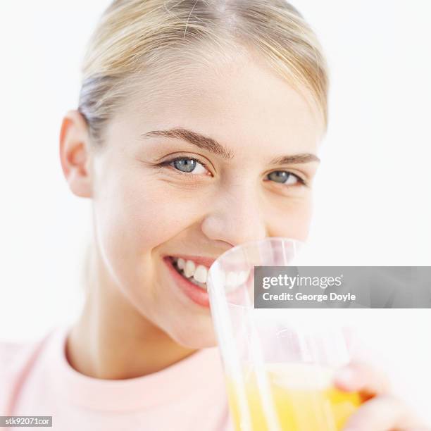 close-up of a woman drinking a glass of orange juice - nur weibliche teenager stock-fotos und bilder