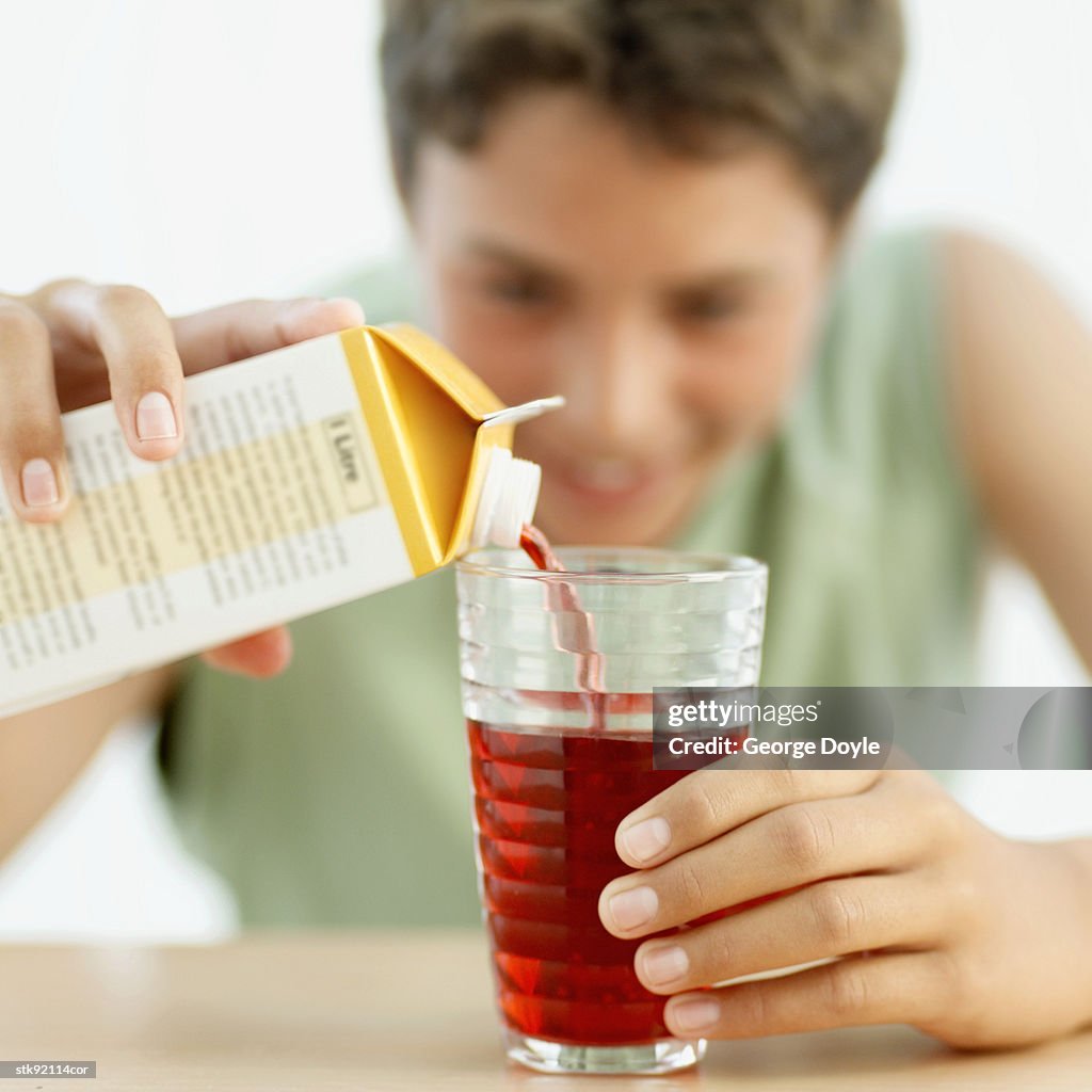 Teenage boy pouring juice into a glass (selective focus)