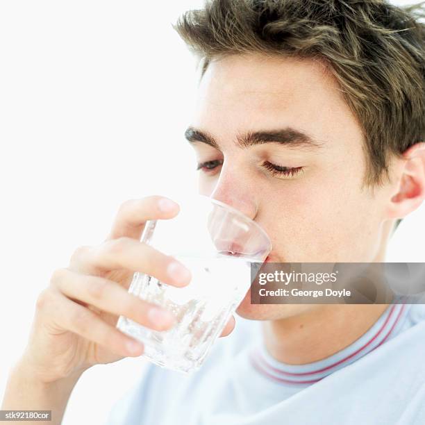 close-up of a teenage boy (16-17) drinking a glass of water - sólo chicos adolescentes fotografías e imágenes de stock