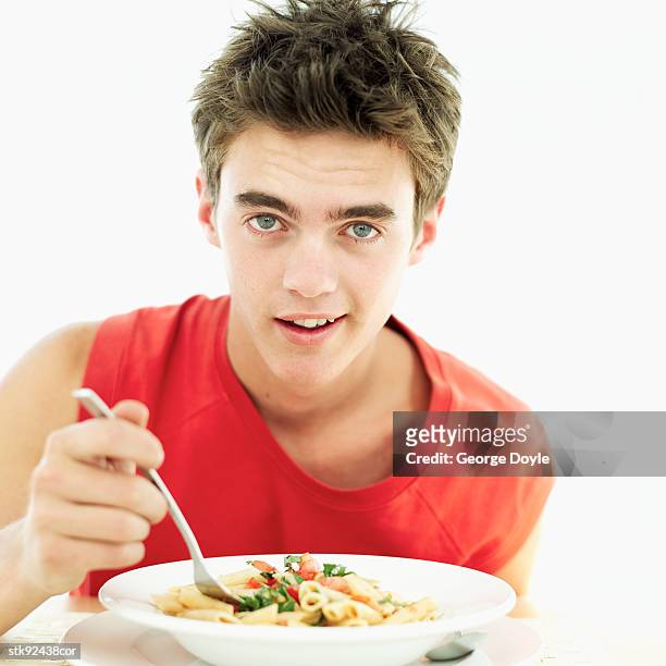 teenage boy (16-17) eating pasta from a bowl - alleen tienerjongens stockfoto's en -beelden