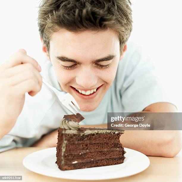 teenage boy (16-17) eating a chocolate cake - alleen tienerjongens stockfoto's en -beelden