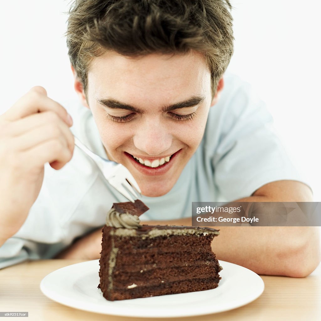 Teenage boy (16-17) eating a chocolate cake