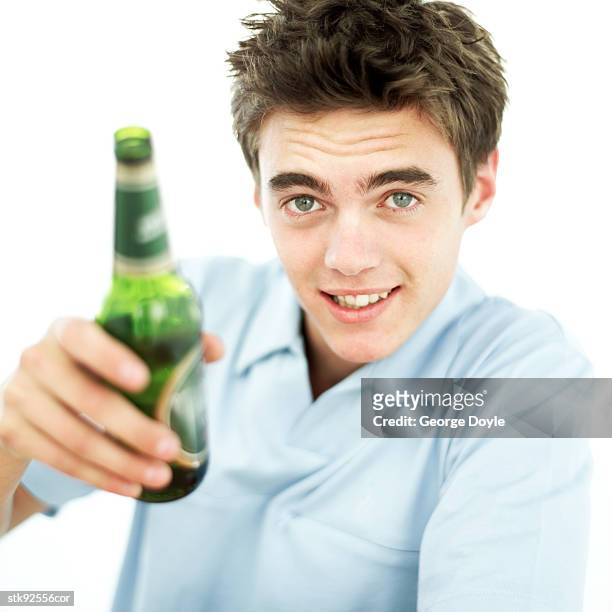 portrait of a young man toasting with a beer bottle - alleen tienerjongens stockfoto's en -beelden