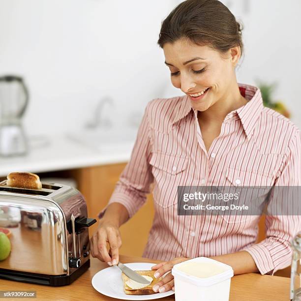 woman spreading butter on toast - alleen mid volwassen vrouwen stockfoto's en -beelden