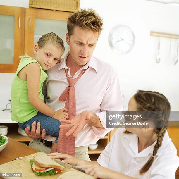 portrait of a father and his daughters in the kitchen - lunch argument stock-fotos und bilder