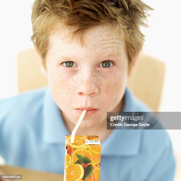 boy (6-7) drinking a carton of orange juice - juice box stock pictures, royalty-free photos & images