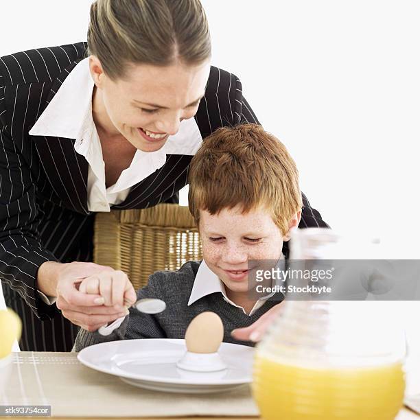 mother helping her son (6-7) eat an egg - her stock pictures, royalty-free photos & images
