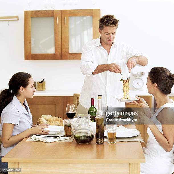 portrait of a young woman being served spaghetti by a young man - by stock pictures, royalty-free photos & images