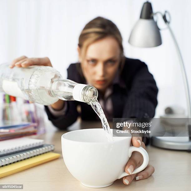 close-up of a businesswoman pouring vodka into her coffee cup - her fotografías e imágenes de stock