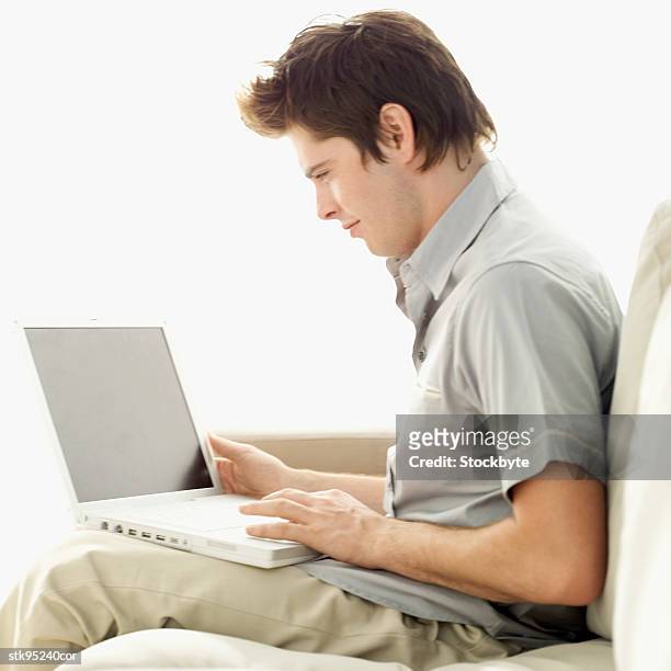 side profile of a man sitting on a couch with a laptop - in profile stock pictures, royalty-free photos & images