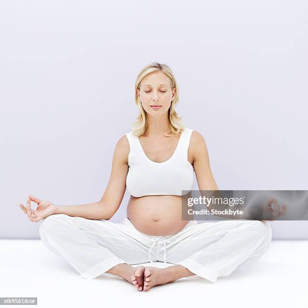 portrait of a young blonde pregnant woman meditating - alleen mid volwassen vrouwen stockfoto's en -beelden