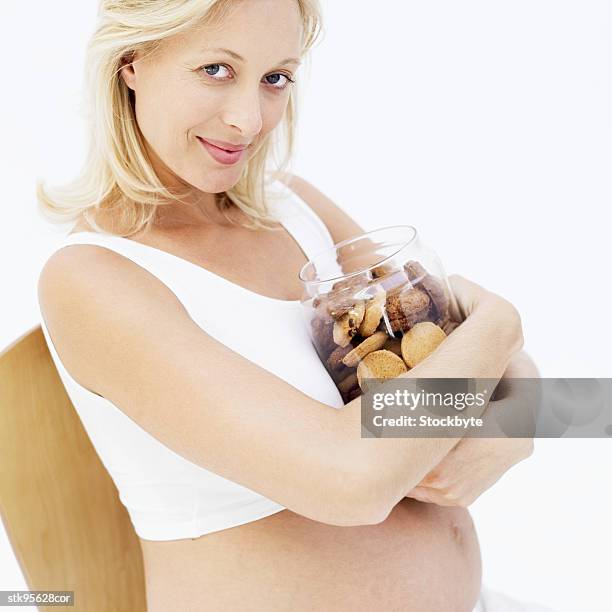 pregnant woman holding a jar of biscuits against her chest - her stock pictures, royalty-free photos & images