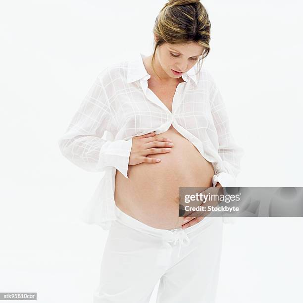 portrait of a pregnant woman with her hands on her stomach - alleen mid volwassen vrouwen stockfoto's en -beelden