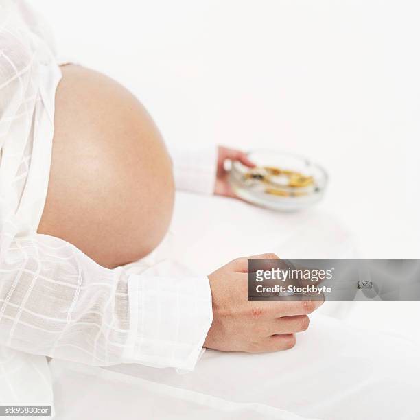 side profile of a pregnant woman holding a cigarette and an ashtray - in profile stock pictures, royalty-free photos & images