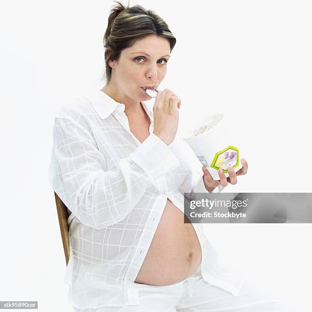 pregnant woman eating ice-cream from a tub - gefrorene süßspeise stock-fotos und bilder