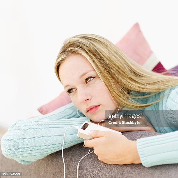 woman wearing headphones listening to an mp3 player - wearing stock-fotos und bilder
