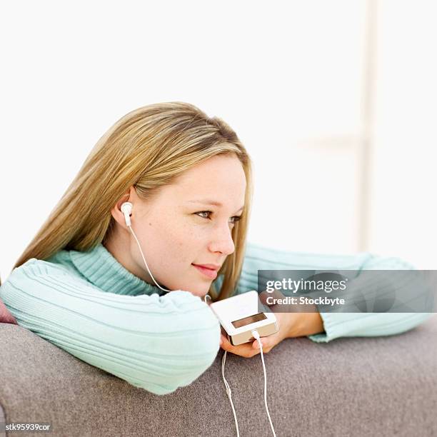 portrait of a young blonde woman listening to music through earphones - audio hardware stock pictures, royalty-free photos & images