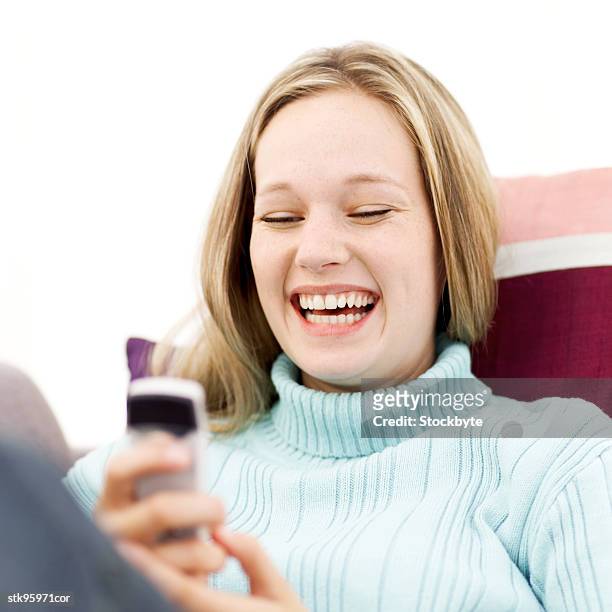 portrait of a young blonde woman operating a mobile phone and laughing - square neckline foto e immagini stock