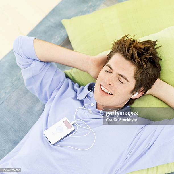 young man lying down and listening to music  - audio electronics stock pictures, royalty-free photos & images