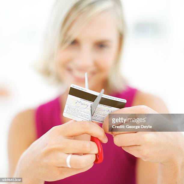 portrait of a young blonde woman destroying her credit card with a pair of scissors - her stock pictures, royalty-free photos & images