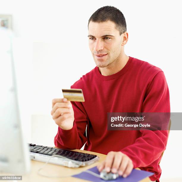 man sitting at the computer holding a credit card - retail of amorepacific corp brands as south koreas biggest cosmetics makers revamps product lineup stockfoto's en -beelden