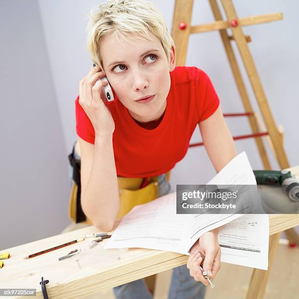 close-up of a woman leaning on a wooden board and holding a mobile phone to her ear - writing instrument stock pictures, royalty-free photos & images