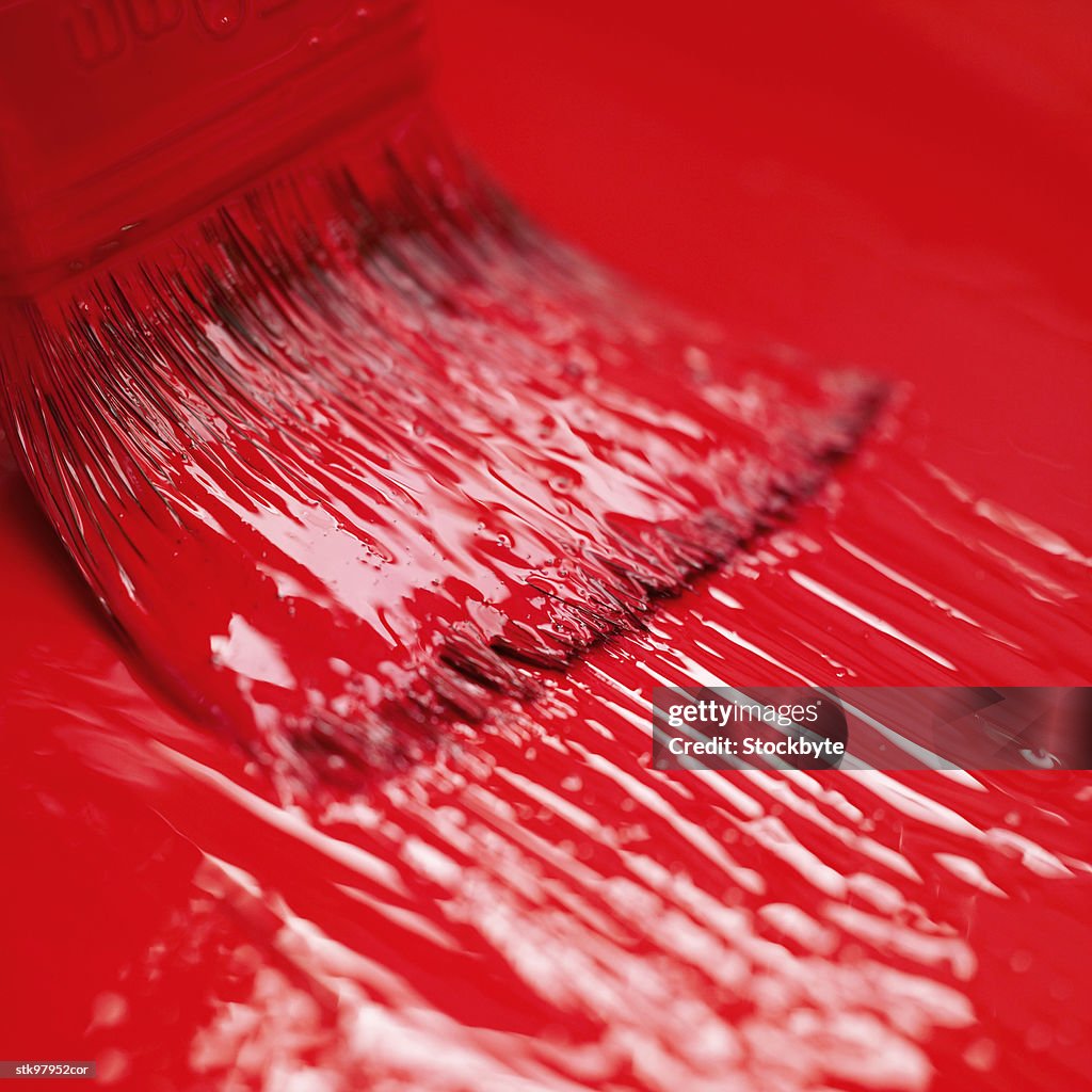 Close-up of a paint brush applying red paint