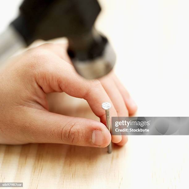 close-up of a boy about to hammer a nail into wood - about stock pictures, royalty-free photos & images