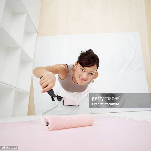 elevated view of woman painting a wall with a roller - roller fotografías e imágenes de stock