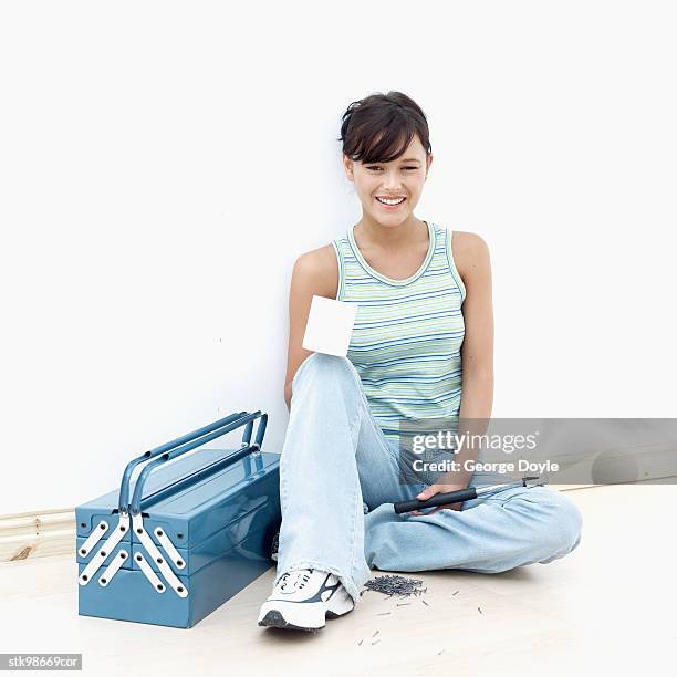 portrait of a woman sitting on the floor next to a tool box holding a hammer and a mug - next stockfoto's en -beelden