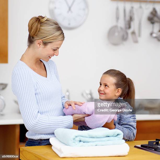 a woman folding towels with her daughter (8-9) - her fotografías e imágenes de stock