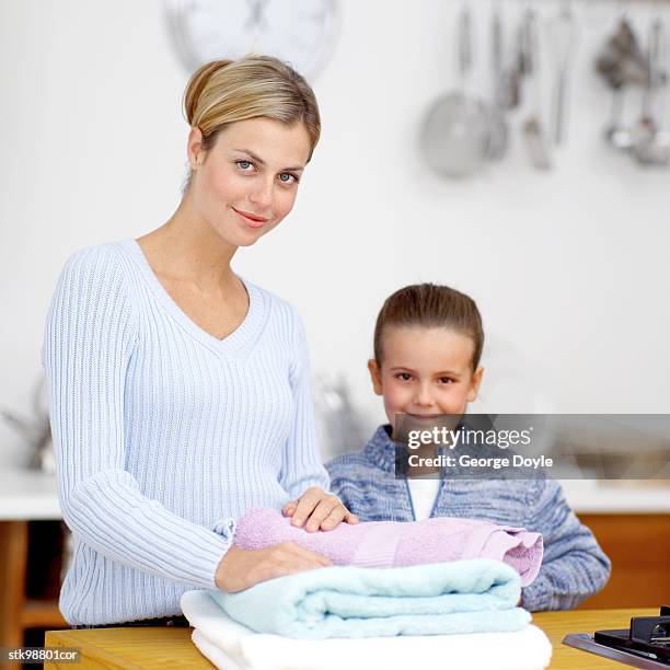 portrait of a mother and her son standing in front of laundered towels - her bildbanksfoton och bilder