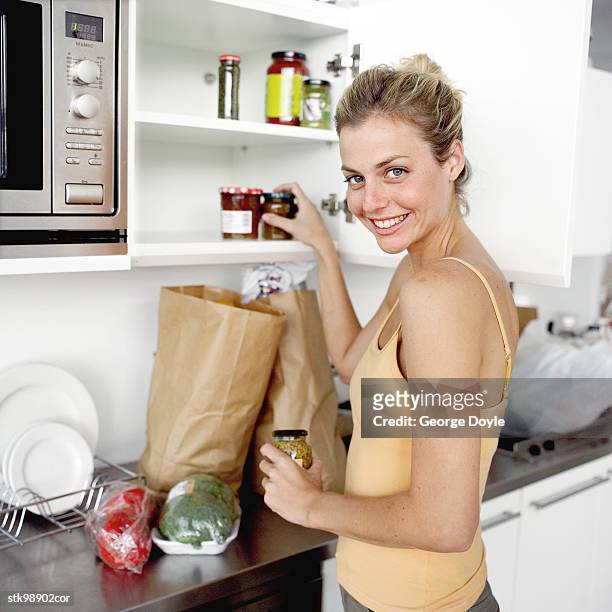 portrait of a young woman replenishing the kitchen cabinets with groceries - the kitchen bildbanksfoton och bilder