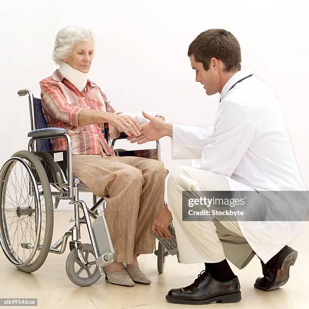 portrait of an elderly woman in a wheelchair shaking a doctors hand - lesión de latigazo cervical fotografías e imágenes de stock
