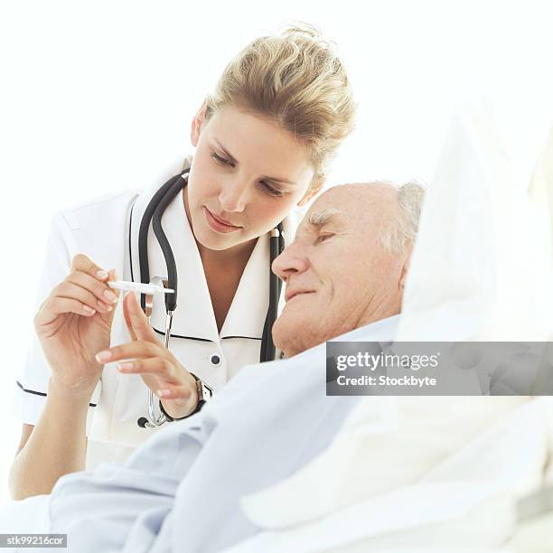 portrait of a nurse showing a thermometer to an elderly patient - screening of la legende de la palme dor after party at china tang stockfoto's en -beelden