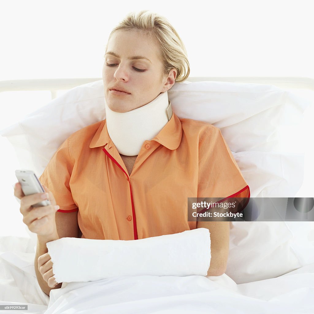 Female patient lying on a bed operating a mobile phone