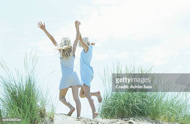 girls holding hands and skipping - menselijke ledematen stockfoto's en -beelden