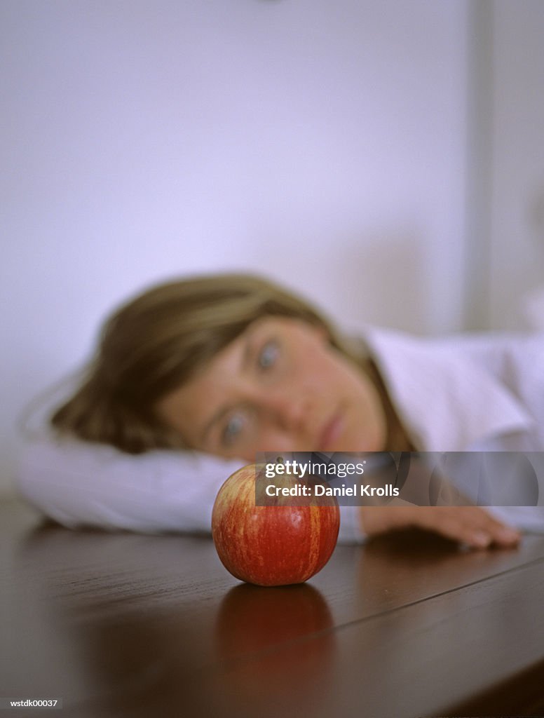 Woman sitting pensively, focus on apple