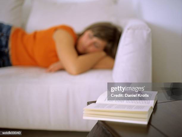 woman lying on sofa, focus on open book - daniel daniel stock pictures, royalty-free photos & images